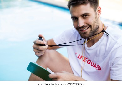 Portrait of lifeguard holding clipboard and stopwatch at poolside on a sunny day - Powered by Shutterstock