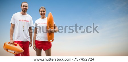 Portrait of lifeguards holding rescue buoy against beautiful sunset on a sunny day
