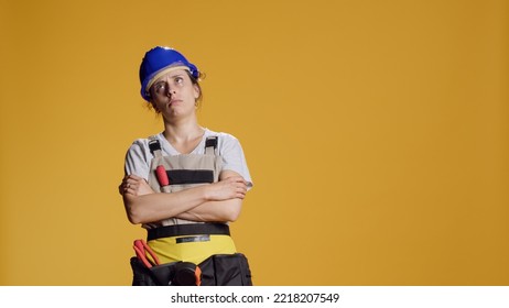 Portrait of light headed contractor being hit in head with hammer, acting dizzy and disorientated. Weak handywoman seeing cartoonish stars and being unsteady or wobbly, looney tunes. - Shutterstock ID 2218207549