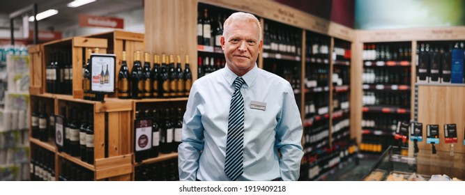 Portrait Of A Liquor Store Manager Looking At Camera. Senior Man Working In A Wine Store.