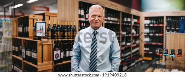 Portrait of a liquor store manager looking\
at camera. Senior man working in a wine\
store.