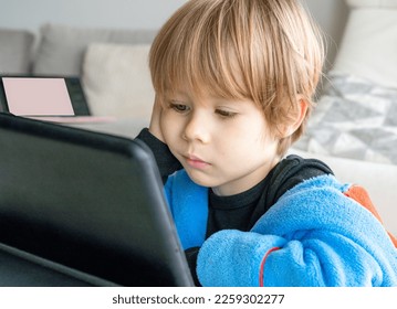 Portrait of little 4 years old boy sitting on living room and using digital tablet computer. - Powered by Shutterstock