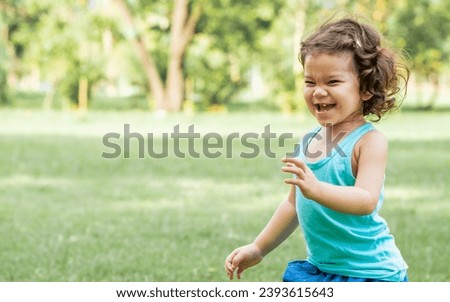 Portrait little adorable cute Caucasian curly hair girl smiling, doing activity, playing, running in outdoor garden during summer holiday with happiness, amusement with copy space. Education Concept