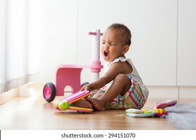 Portrait of little African American little girl sitting on the floor and playing  - Black people