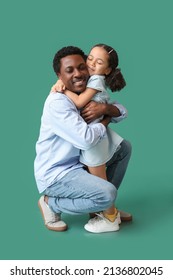 Portrait of little African-American girl hugging her father on green background - Shutterstock ID 2136802045