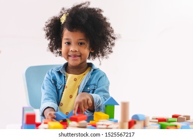Portrait Of Little Afro Girl Smiling And Playing Colorful Wooden Toys At Kindergarten.