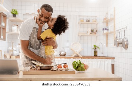 Portrait of little American African black boy parent cooking preparing food with pan in the counter kitchen. Happy  family with father son, father's day, healthcare cooking plant based food concept - Powered by Shutterstock