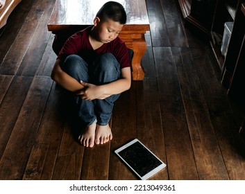 Portrait Of A Little Asian Boy, Kid Sad Face, Unhappy Child Sitting Hug Knees He Looked At The Broken Tablet Computer On The Ground., Emotion Sad And Sad Face, Depressed Children Concept