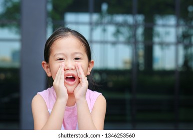 Portrait Little Asian Child Girl Acting And Shouting Through Hands Like Megaphone. Communication Concept.