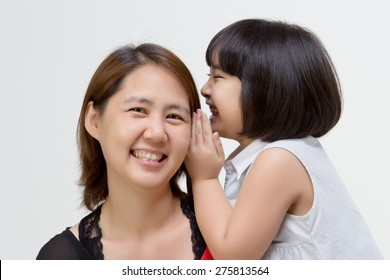 Portrait Of Little Asian Child Whispering To Her Mother