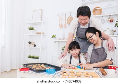 Portrait Of Little Asian Girl And Her Parents Baking Cooking Cake And Cookies In The Kitchen. Happy Asian Family And Mother's Day, Healthcare Food Cooking Concept