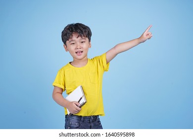 Portrait of little Asian kid student with pencil and notebook, isolated on blue background - Shutterstock ID 1640595898