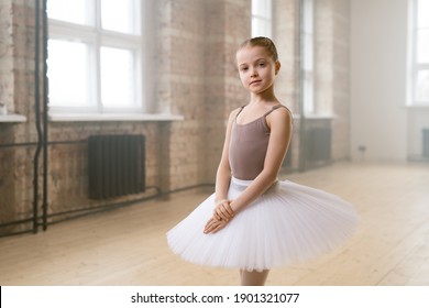 Portrait Of Little Ballet Dancer In Tutu Dress Looking At Camera Standing In Dance School