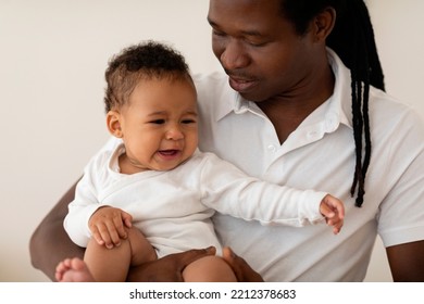 Portrait Of Little Black Baby Crying In Father's Arms, Caring African American Dad Comforting His Upset Infant Child Suffering Colic Or Teething While Bonding Together At Home, Cropped