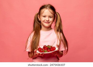 Portrait of a little blonde girl in pink t-shirt eating strawberry against pink background. GMO free food. Kids eat fruit outdoors. Healthy snack for children. summer concept. High quality photo - Powered by Shutterstock