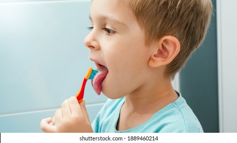 Portrait of little boy brushing teeth and cleaning tongue with toothbrush. CHild taking care of teeth and cleaning them.