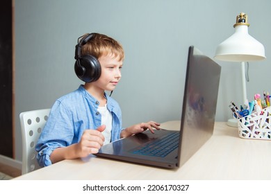 Portrait Of Little Boy In Headset Laptop, Studying Online At Home, Interested Happy Student Typing On Keyboard Looking At Pc Screen, Watching Webinar, Online Course, Doing Homework