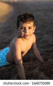 Portrait Of Little Boy Lying Down On The Sand