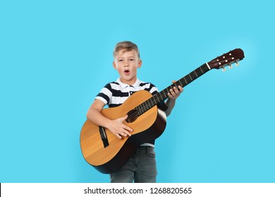 Portrait of little boy playing guitar on color background