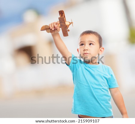 portrait of a little boy playing with a wooden plane