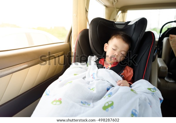 Portrait of Little Boy Sleeping in Car\
Seat, image with toning and effect of soft shining\
sun