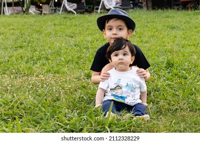 Portrait of little brothers sitting on the grass.