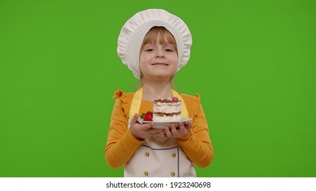Portrait of little child girl kid dressed as professional cook chef baker eating tasty strawberry cake isolated on chroma key background. Concept of sweet nutrition food, cooking school, education - Powered by Shutterstock - Get 15% off with code: PIKWIZARD15