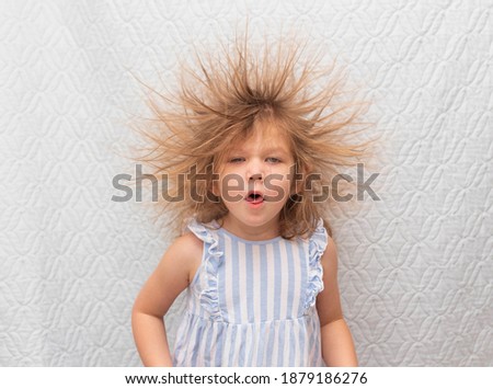 Portrait of a little coughing girl with electrified hair on a white background.
Electricity power concept.