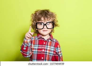 Portrait of a little curly boy in glasses on a bright green background. Little scientist, inventor, researcher, physicist, mathematician. - Shutterstock ID 1577494939