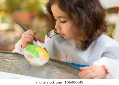 Portrait Of Little Curly Child Painting, Summer Outdoor.Kid Drawing On A Stone.