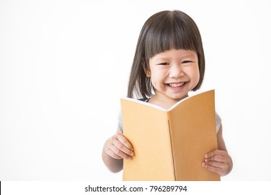 Portrait Of Little Cute Asian Toddler Girl Reading A Book Isolated On White Background. Home School And Education Study Concept