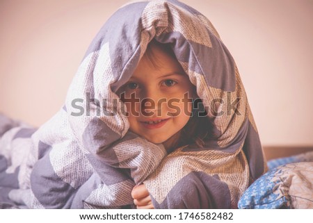 Portrait of little cute child girl before bedtime under the blanket. Sleep and relax concept.