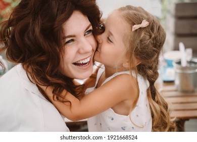 Portrait of little daughter kissing her beautiful happy mother - Shutterstock ID 1921668524