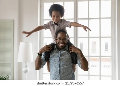 Portrait Of Little Ethnic Boy Child Sit On Shoulders Play With Excited African American Dad At Home. Smiling Young Father Carry On Back, Have Fun Enjoy Family Weekend Together With Small Son