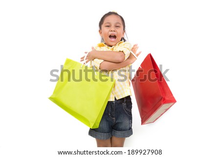 Portrait of a little fashion shopping girl with shopping bags, isolated over white