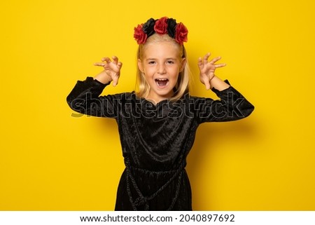 Portrait of little girl in black clothing isolated over yellow background.