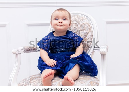 portrait of a little girl in a blue dress sitting on a chair in the form.