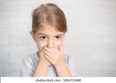 portrait of little girl, child closing his mouth with hands. Speech therapist, speech problems, stammering, mumbling.