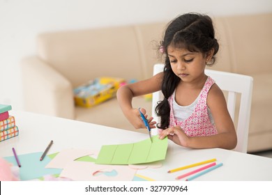 Portrait of a little girl cutting a paper