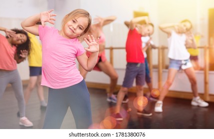 Portrait Of Little Girl Doing Exercises During Group Class In Dance Center