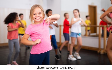 Portrait Of Little Girl Doing Exercises During Group Class In Dance Center