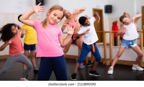 Portrait Of Little Girl Doing Exercises During Group Class In Dance Center