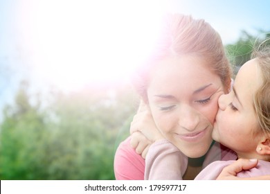 Portrait Of Little Girl Giving Kiss To Her Mom