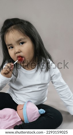 Portrait of a little girl holding a lollipop on a stick. The concept of childhood