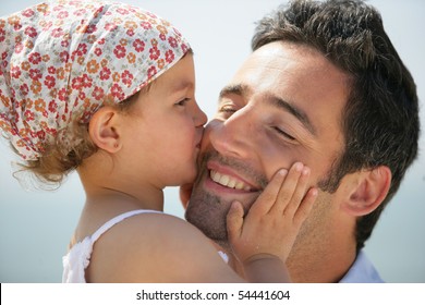 Portrait of a little girl kissing a man on the cheek - Powered by Shutterstock