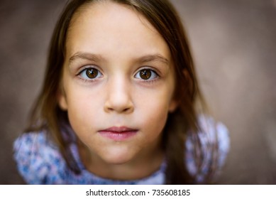 Portrait of little girl looking up at the parent outdoors. A child is looking up towards the camera outside in the woods. Shallow depth of field and soft selective focus on the eyes.