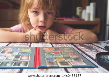 portrait of a little girl looking postage stamps on the table