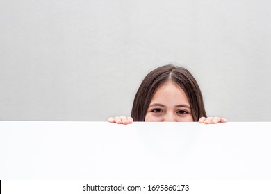 Portrait Of Little Girl Looking From Under The Table Isolated On White Background