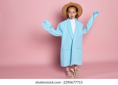 Portrait of a little girl in an oversized adult blue blazer and a round brown hat. Child wearing adults clothes. Isolated on pink background. - Powered by Shutterstock