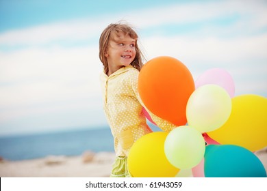 Portrait of little girl playing with air balloons at the beach - Powered by Shutterstock
